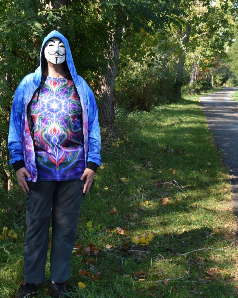 Joe in Guy Fawkes mask standing in woods.